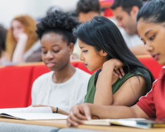 Two students together at a lecture looking at their notes